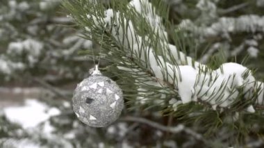 Noel ağacı oyuncağı bir Noel ağacının karla kaplı dalına asılır. Kış karlı ormanı..