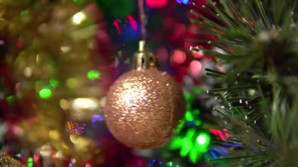 Egy gyönyörű fényes labda lóg és forog a karácsonyfán.Homályos háttér egy fa. — Stock videók