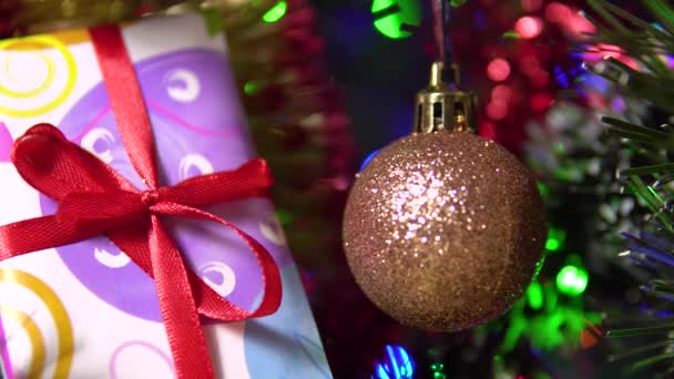 Egy gyönyörű fényes labda és egy ajándékdoboz lóg a fáról. Újévi ünneplés. — Stock videók