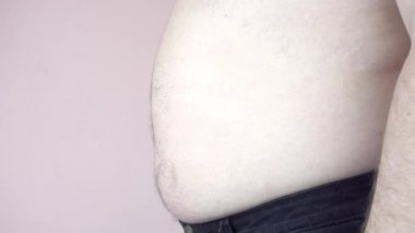 Adam içeri giriyor ve karnını şişiriyor. Adamın göbeği kocaman. Obezite. Yakın plan..