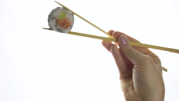 Female hand holding sushi with chopsticks isolated on white background. Close-up. — Stock Video