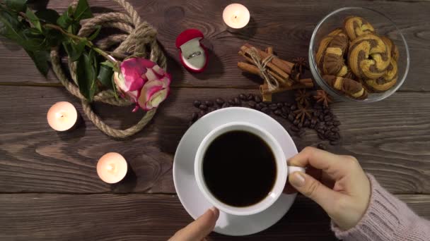 Uma mulher coloca uma xícara e pega uma xícara de café em uma mesa decorada romanticamente. — Vídeo de Stock