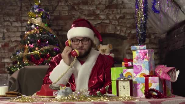 Lustige Weihnachtsmänner sprechen auf dem alten roten Telefon, während sie auf der Couch sitzen.. — Stockvideo