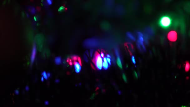 Unscharfer Hintergrund. Die farbigen Lichter der Girlande blinken am Weihnachtsbaum. — Stockvideo