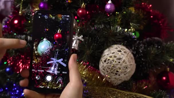 Una mano femminile fa una foto di un albero di Natale elegante utilizzando uno smartphone.Photo per i social network — Video Stock