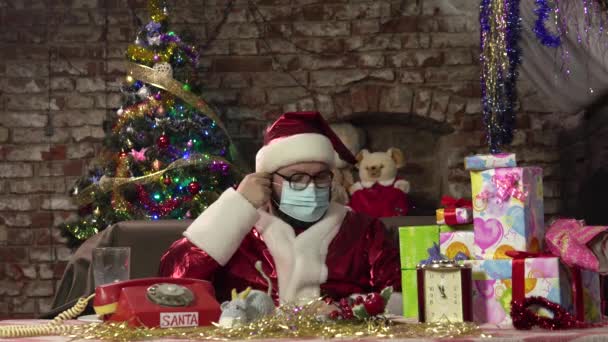 Santa Claus se quita la máscara protectora del virus y se apoya en el sofá para relajarse. — Vídeo de stock