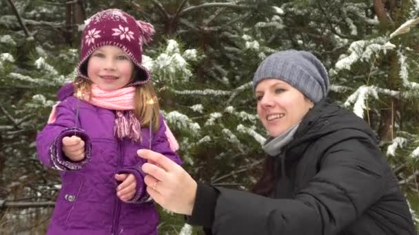 Мати і її маленька донька дивляться на палаючі блискавки в зимовому лісі . — стокове відео