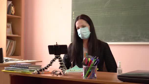 L'insegnante con una maschera protettiva.Un giovane insegnante conduce una lezione, filmandosi su uno smartphone. — Video Stock