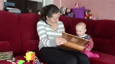 Genç anne bebekle kitap okuyor.