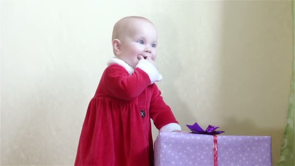 Ребенок стоит рядом с коробкой с подарком — стоковое видео