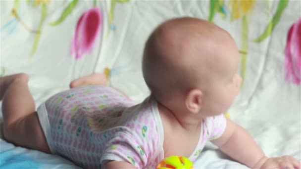 Baby liggande på sängen och lyfter huvudet — Stockvideo