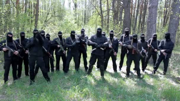Terroristák lőnek a levegőbe.A fekete maszkos és ruhás emberek fegyverrel állnak az erdőben. — Stock videók