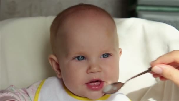 A mãe alimenta a criança com uma colher de mingau de cereal — Vídeo de Stock