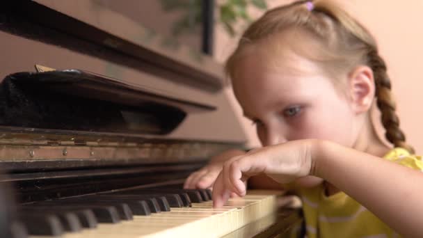 Ένα όμορφο κορίτσι έβαλε το κεφάλι της στα πλήκτρα του πιάνου. Ένα κοριτσάκι παίζει πιάνο σε ένα μάθημα μουσικής.. — Αρχείο Βίντεο