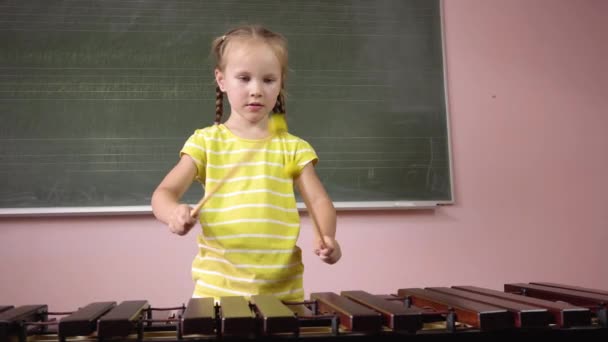 Una niña pequeña toca el xilófono en una clase de música. — Vídeos de Stock