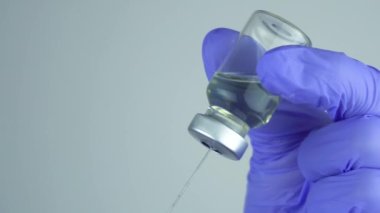 Şırıngayı, klinikteki bir hastanın aşısı için bir şişeden çıkan solüsyonla doldurmak..