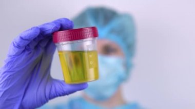 Kadın doktor idrar testi yapılan bir kap gösterdi..