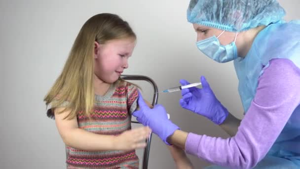 医者は少女にワクチンを注射する。女の子は恐れて泣いている. — ストック動画