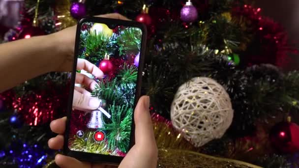 Egy női kéz készít egy képet egy karácsonyfa elegáns segítségével egy okostelefon.Photo a szociális hálózatok — Stock videók