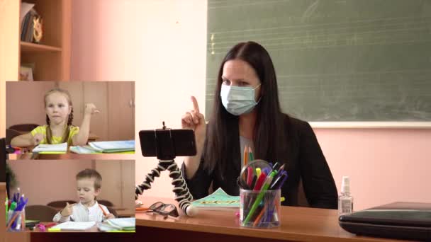 Incontro virtuale online di un insegnante in maschera protettiva e piccoli studenti. Collage sullo schermo — Video Stock