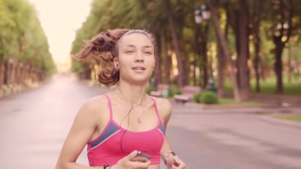 Gyönyörű fiatal lány képzés fut a parkban, lassú mozgás — Stock videók