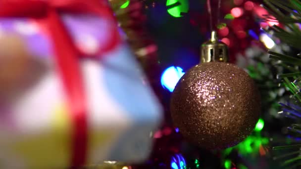 Una mano femminile mette una piccola confezione regalo con un nastro rosso sotto l'albero.Capodanno. — Video Stock