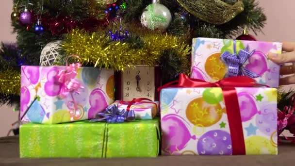 Una mano femenina pone cajas de regalo bajo el árbol de Navidad.Años nuevos por la noche.Muchos regalos. — Vídeos de Stock