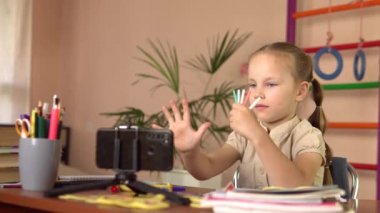 Anaokulundan bir kız sopa sayıyor, akıllı telefona bakıyor ve bir soruya cevap veriyor. Matematik dersi.