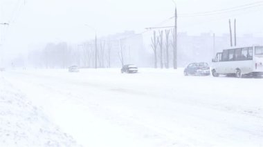 Kar fırtınasında arabalar yolda ilerliyor.