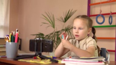 Anaokulundan bir kız sopa sayıyor, akıllı telefona bakıyor ve bir soruyu cevaplıyor..