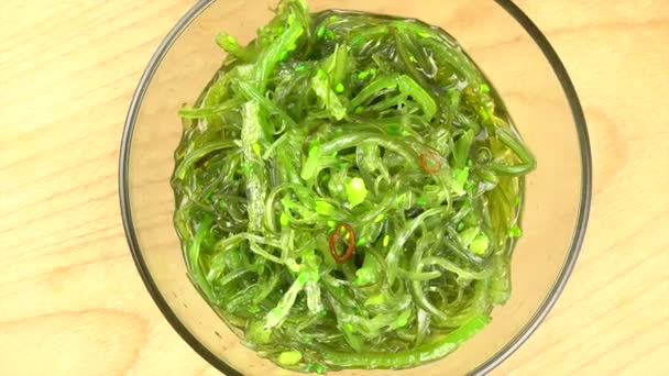 Chuka seaweed in a glass bowl on a wooden stand. Close-up from above. Rotation. — Stock Video