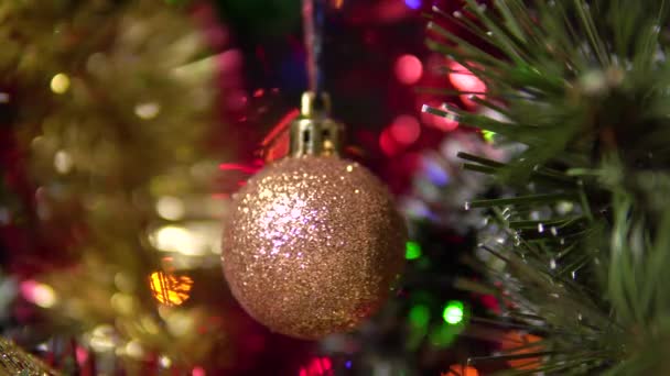 Egy gyönyörű fényes labda lóg és forog a karácsonyfán.Homályos háttér egy fa. — Stock videók