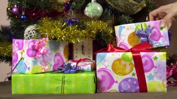 Een vrouwelijke hand legt geschenkdozen onder de kerstboom.Nieuwjaarsavond. — Stockvideo