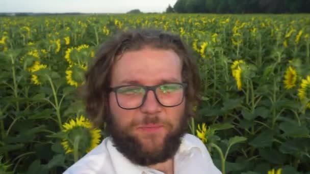Um jovem barbudo está transmitindo um vídeo de um campo de sunflowers.Farmer consulta online. — Vídeo de Stock