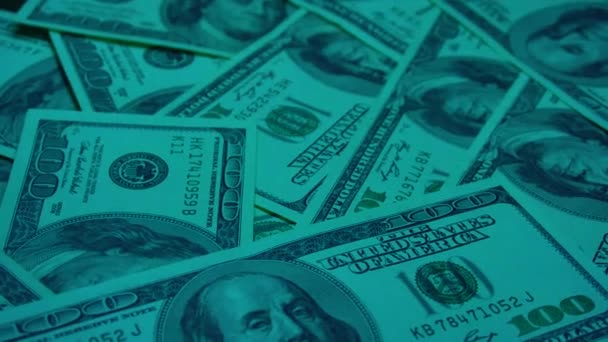 Банкноты по сто американских долларов, лицом вверх, вращающиеся по кругу под ультрафиолетовым светом. — стоковое видео