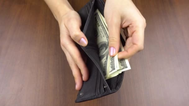 Vrouwen hand nemen contant geld van een mans portemonnee. Vrouwen handen houden een portemonnee vast en tellen dollars erin. — Stockvideo