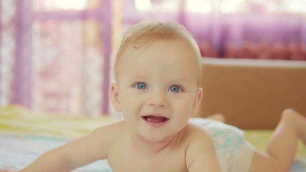 Um lindo bebê está em sua barriga, olha para a câmera e sorri. — Vídeo de Stock
