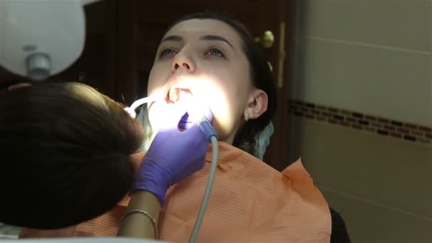 Mladá žena na zubní klinice. Čištění zubů. — Stock video
