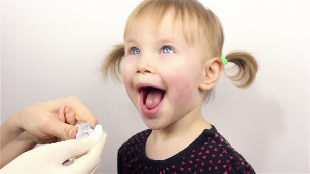 Bőrápolás. Egy gyönyörű kislány portréja, anya hidratáló krémet tesz az arcára.. — Stock videók