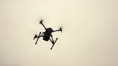 Gökyüzünde kameralı insansız bir helikopter geziniyor. Modern askeri İHA.