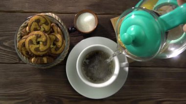 Bir kadın eli çaydanlığı tutar ve siyah çay demlemek için bir kaba kaynar su döker..