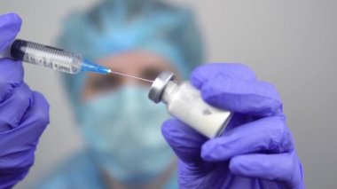 Doktor kuru ilaçla şırıngadaki sıvıyı steril bir şişede karıştırıyor. Yakın plan..