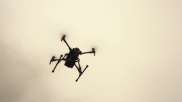 Ein unbemannter Hubschrauber mit Videokamera schwebt am Himmel. Moderne militärische Drohne. — Stockvideo