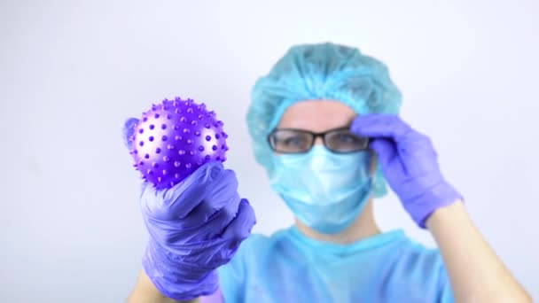Femme médecin, tient un coronavirus dans sa main et le regarde. — Video