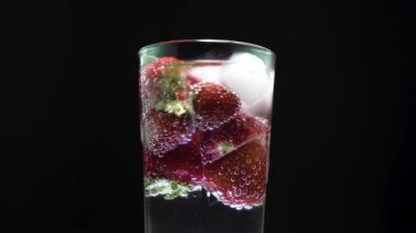 Buzlu ve çilekli uzun cam soda, orta ekran. Köpüklü kabarcıklar yükseliyor.