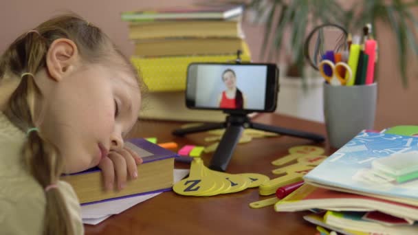 小さな女の子は、画面上のスマートフォンでテーブルで寝ています,先生. 4k — ストック動画