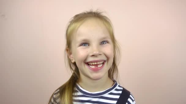 5-6 yaşındaki güzel bir kız süt dişleriyle ağzını gösteriyor. Gülümsüyor ve yüzünü buruşturuyor.. — Stok video
