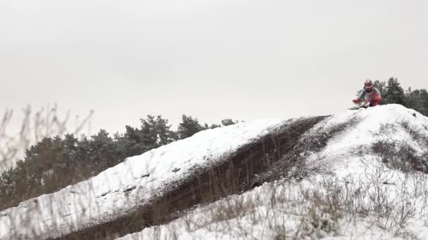 KHARKIV, UKRAJINA - 1. Prosinec 2020: Motorkář sjíždí z přírodního nečistého odrazového můstku na motokrosové motorce po prvním sněhu. . — Stock video
