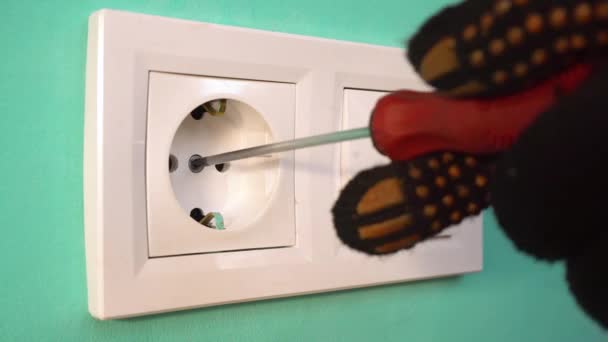 Een elektricien in zwarte handschoenen installeert een stopcontact. Close-up - stopcontact. — Stockvideo