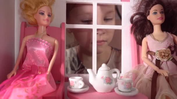 Uma menina olha para fora a janela de um dollhouse.Furniture para toys.Toy house.Toy utensílios de mesa. — Vídeo de Stock